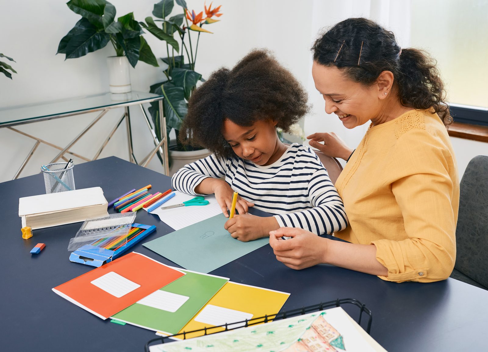 A parent and child working together at home on a drawing activity