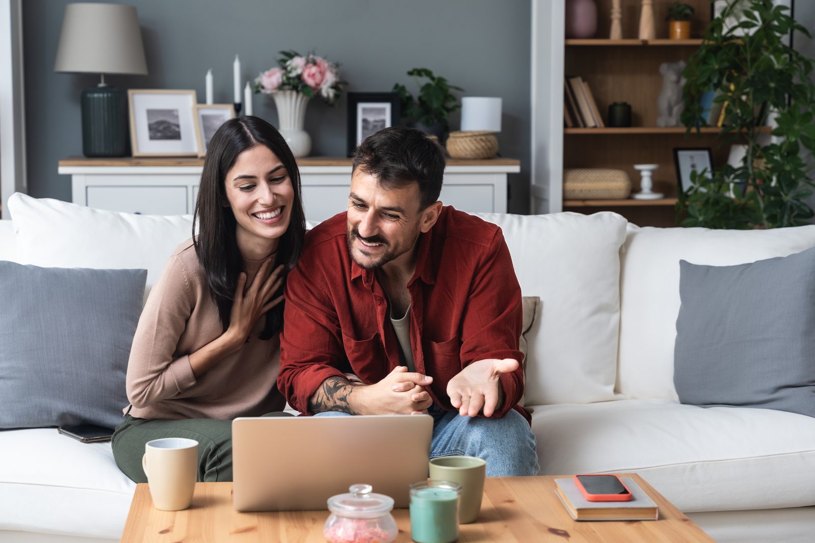 A couple smiling together while looking at a laptop